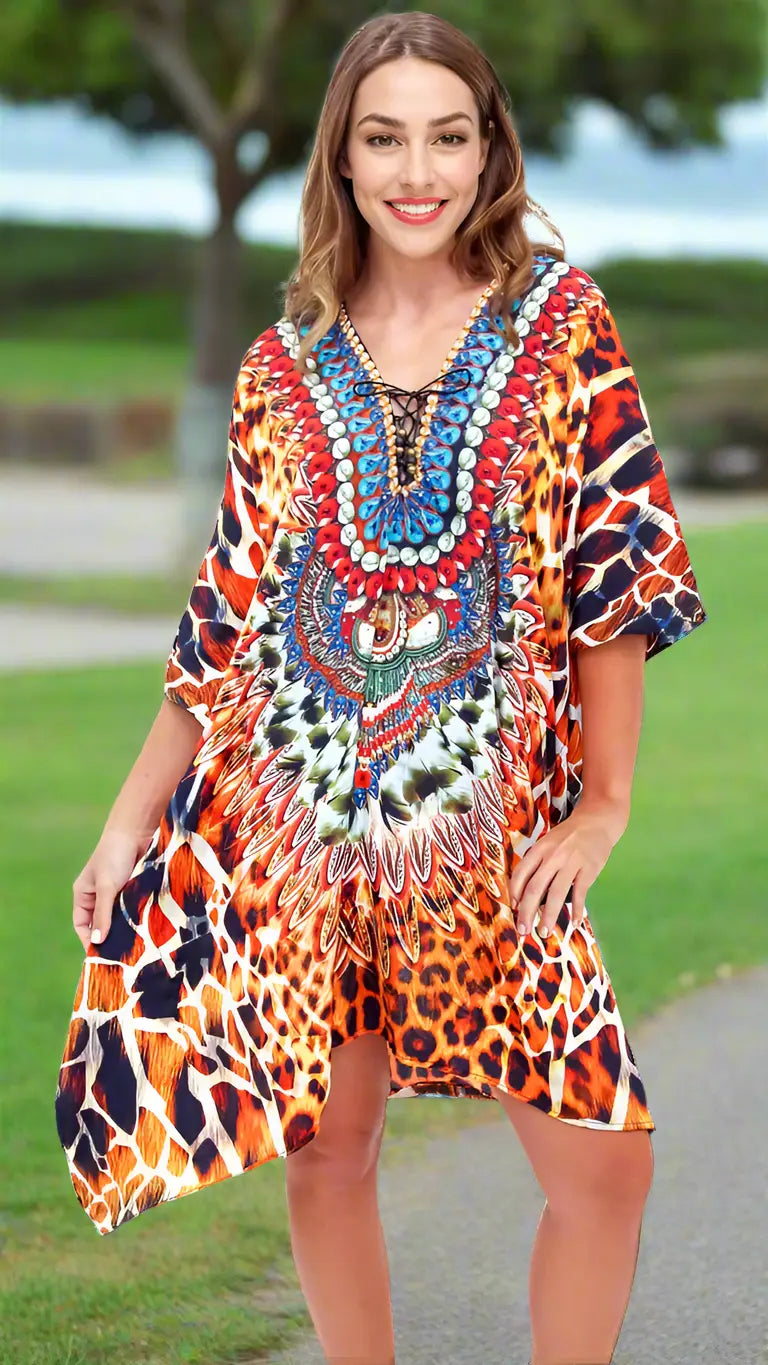 A woman smiles outdoors on green grass, wearing the lamodaclothings Animal Prints Caftan—a loose, vibrant piece with bold multicolored animal and feather prints in orange, brown, blue, and red—capturing a bright and joyful summer vibe.
