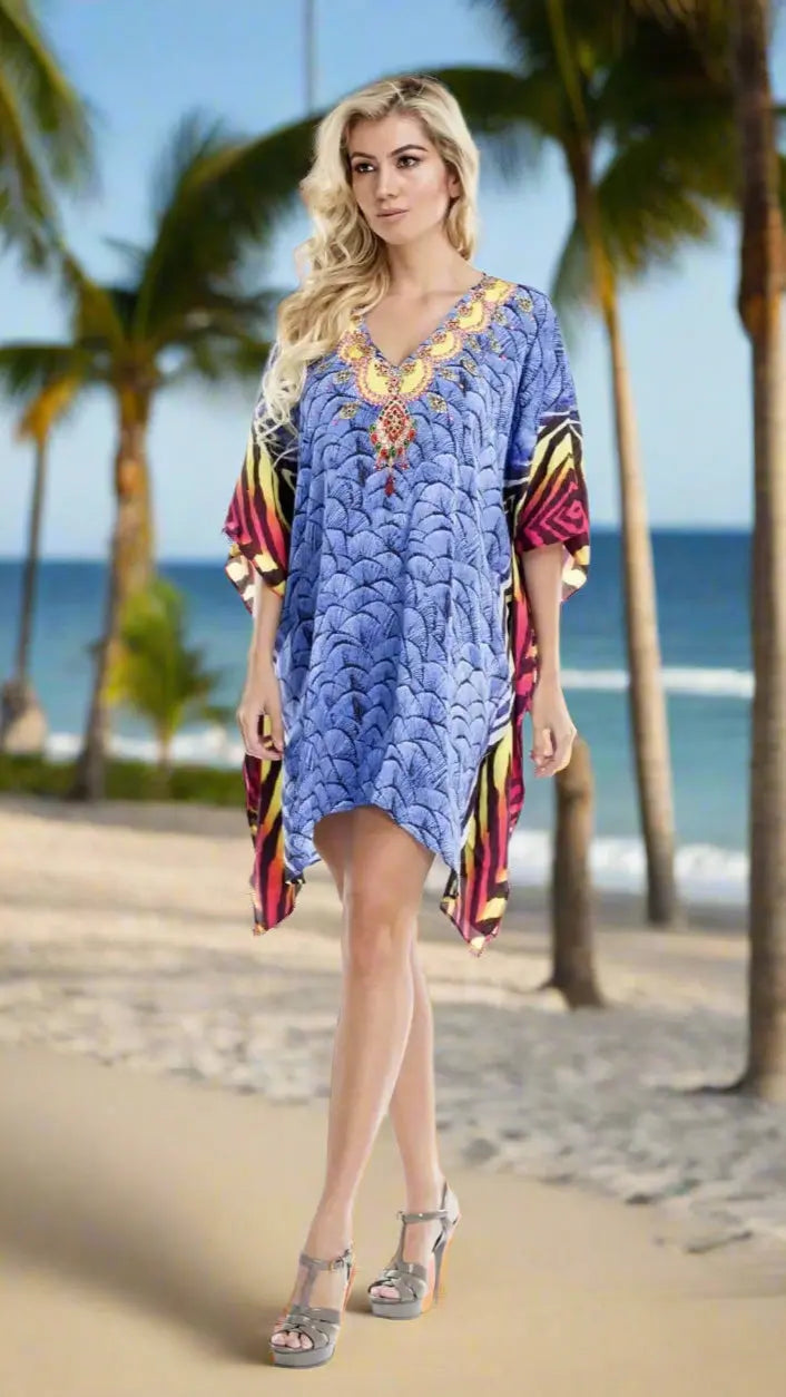On a sandy beach with palm trees and ocean behind her, a woman in the lamodaclothings Multi Color Sheer Kaftan Cover Up and gray high-heeled sandals gazes right, her long blonde hair loose and expression relaxed.