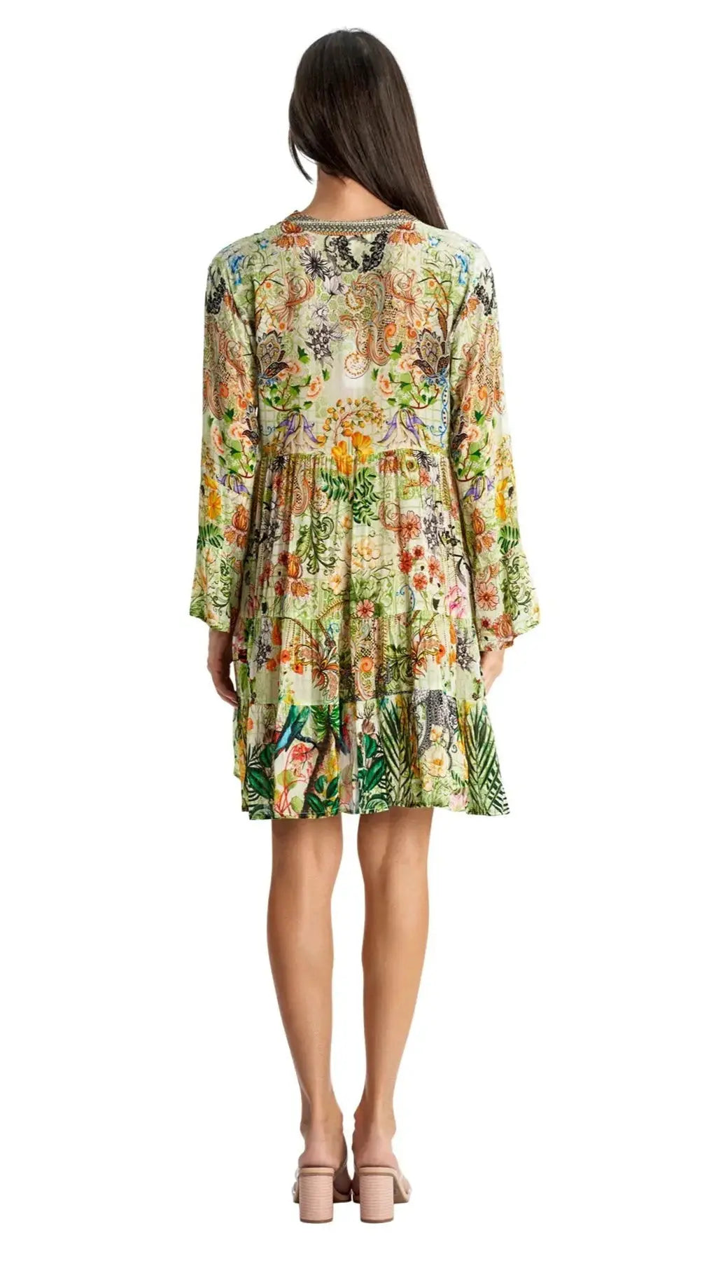 A woman with long dark hair faces away, wearing the La Moda Clothing Mini Dress for beach resort & cruise—a loose, knee-length floral and paisley piece with long sleeves and beige heeled sandals—ideal for any vacation wardrobe.