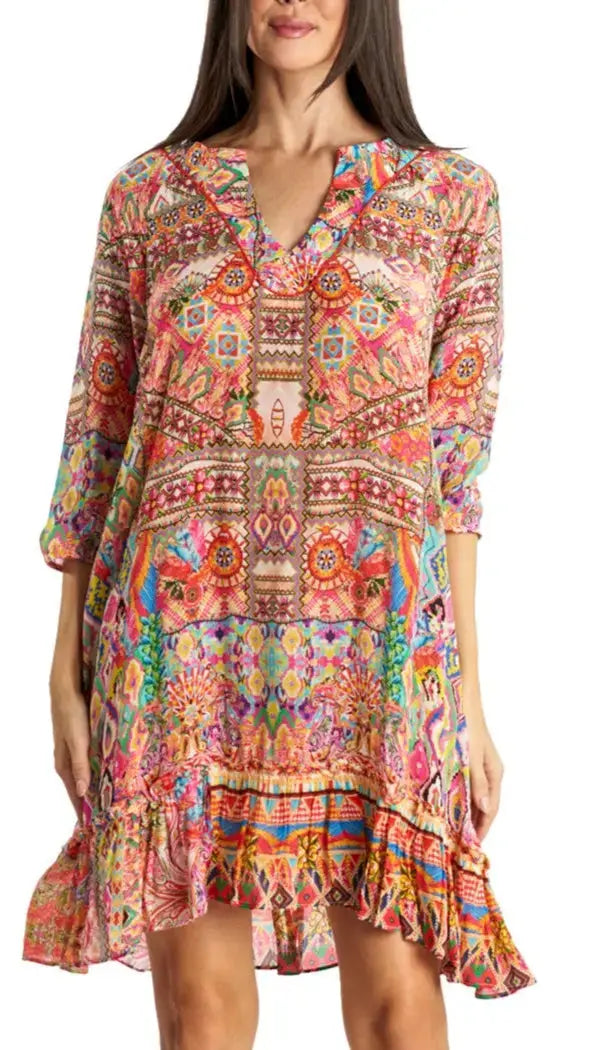 A woman wears La Moda Clothings Short Dress, featuring a loose fit, long sleeves, a V-neckline, vibrant geometric and floral prints, ruffled hem, and above-the-knee length—an ideal versatile summer wardrobe piece.